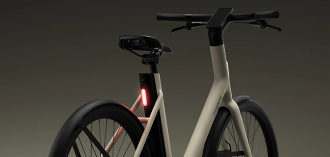 Rear view of a beige electric bike frame with an integrated glowing red tail light.